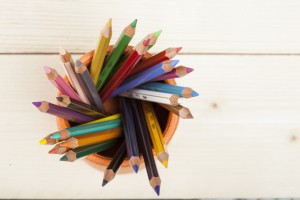 Matite colorate dentro porta penne su piano di legno